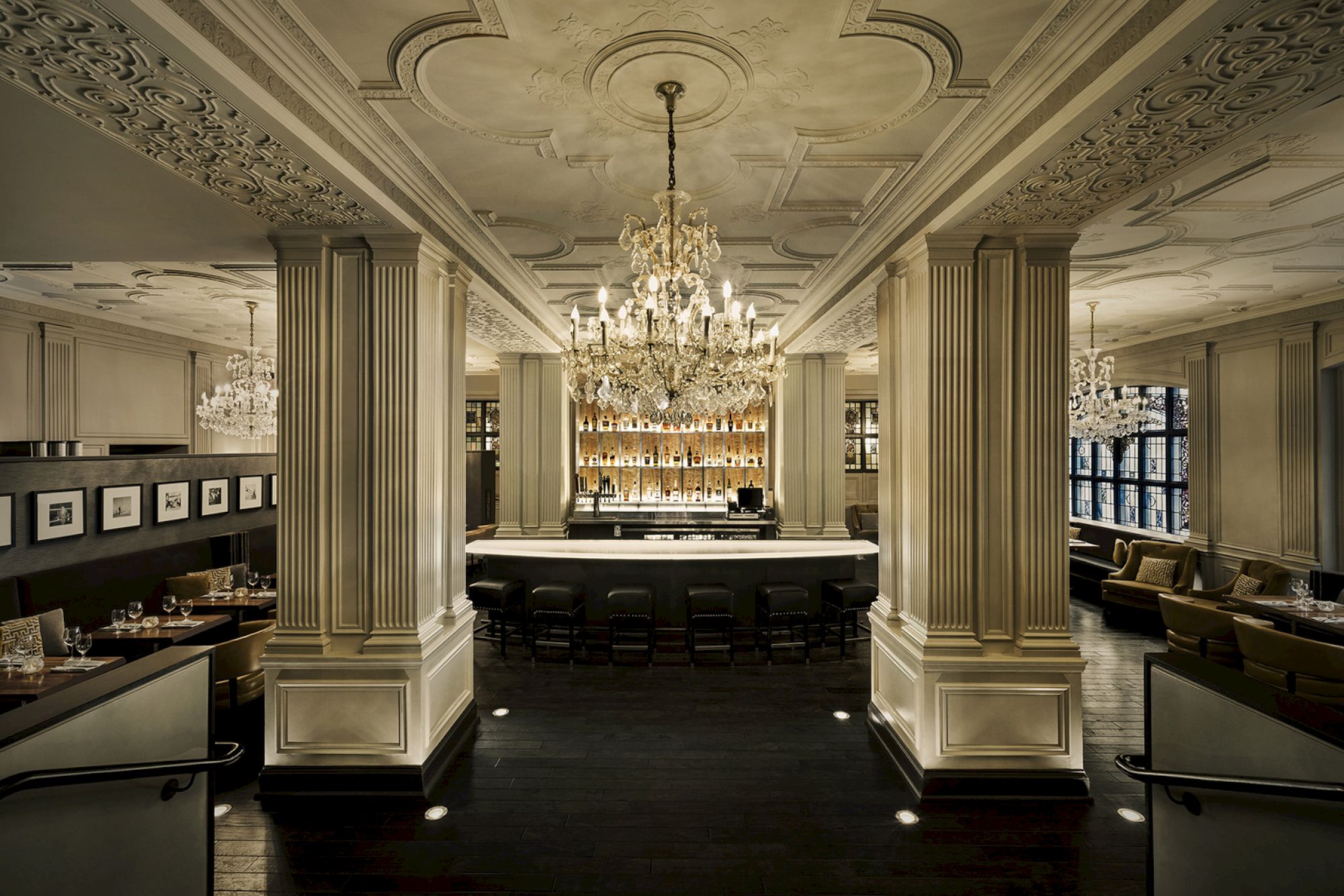 An elegant restaurant interior with ornate chandeliers, long tables, and cozy booths surrounded by intricate architectural details and ambient lighting.